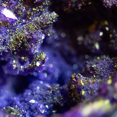 Primerísimo plano de una piedra con brillos de varios colores azulados, dorados y violetas